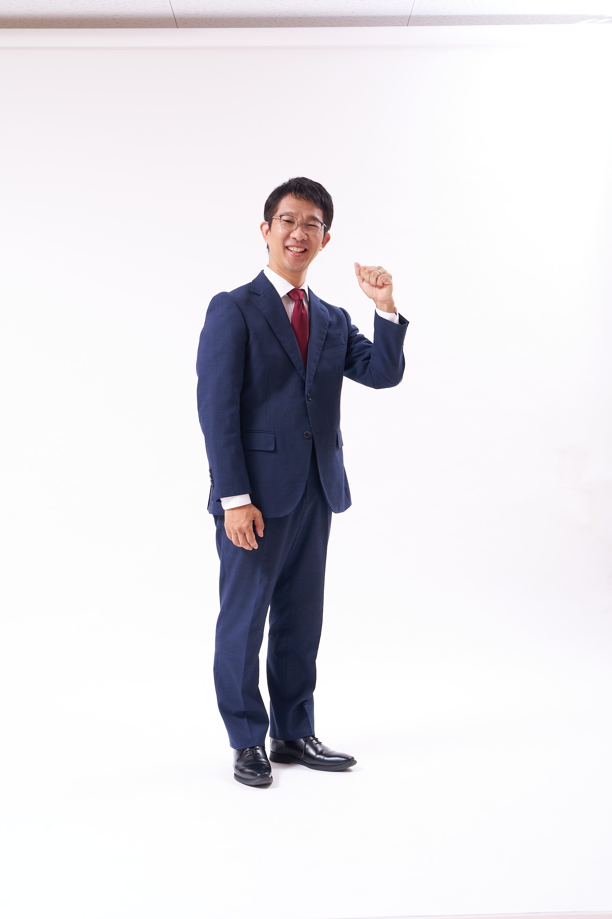 笑顔で拳を上げる光森伸作のスタジオ写真